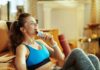 Woman in sportswear eating a snack bar on a couch