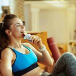 Woman in sportswear eating a snack bar on a couch