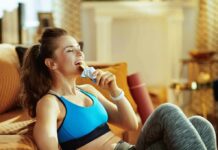 Woman in sportswear eating a snack bar on a couch