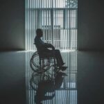 Person in a wheelchair silhouetted by a large window