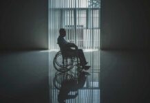 Person in a wheelchair silhouetted by a large window