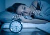 Chronic Insomnia’s Hidden Price Woman lying awake in bed beside an alarm clock