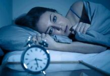 Chronic Insomnia’s Hidden Price Woman lying awake in bed beside an alarm clock