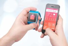 hands holding a smartwatch and a smartphone with health app