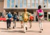 Group of schoolchildren with backpacks running toward a school entrance
