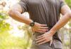 When Back Pain Signals Something Much Deeper person holding lower back outdoors