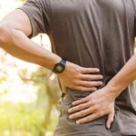 person holding lower back outdoors