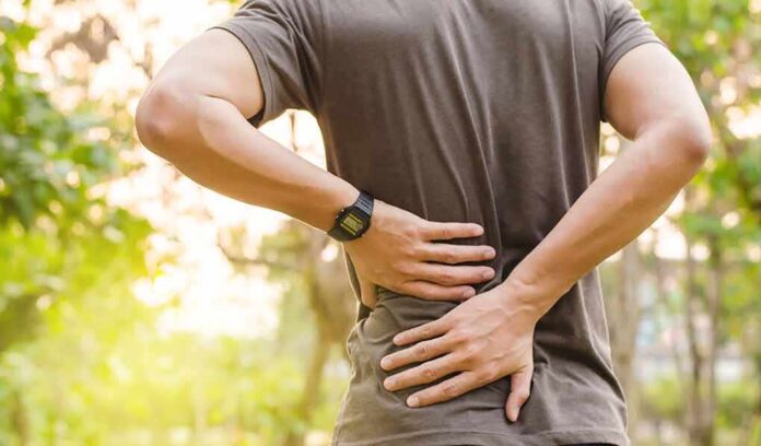 shutterstock_607977332 person holding lower back outdoors