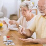 Older couple organizing medication at a kitchen table
