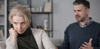 Woman on couch looking away as man gestures during argument