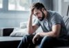 Stanford Flags Shocking Depression Driver Man sitting on couch with head in hand