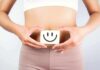 How to Enhance Your Gut Microbiome for Overall Health torso of person holding smiley card over stomach