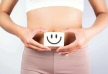 How to Enhance Your Gut Microbiome for Overall Health torso of person holding smiley card over stomach