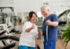 Older man and woman smiling with measuring tape in a gym