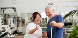 Older man and woman smiling with measuring tape in a gym