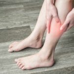 person holding calf with red area indicating leg pain
