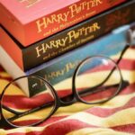 Round black glasses on striped scarf beside Harry Potter books