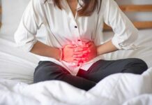 How often should you poop? Understanding Frequency and Normalities Woman holding her abdomen in pain while sitting on a bed
