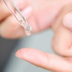 dropper applying clear liquid to fingertip