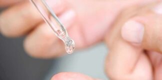 dropper applying clear liquid to fingertip