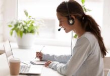 Woman with headset taking notes at a laptop