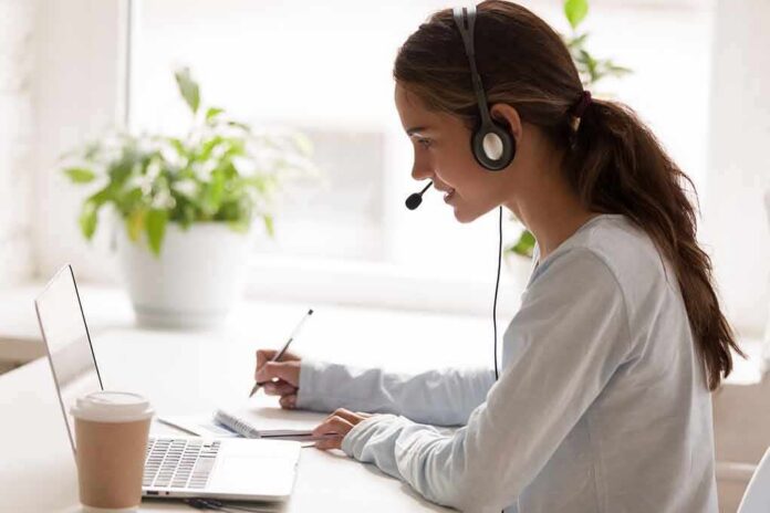 Woman with headset taking notes at a laptop