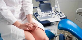Patient on gynecological exam chair beside ultrasound machine