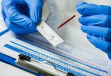 DNA Test Cracks Deadly Bugs In Hours Gloved hands using a rapid test cassette with a blood sample dropper