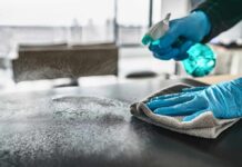 Gloved hands spraying and wiping a tabletop
