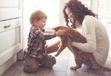 Harvard Shatters Pet-Happiness Myth toddler petting orange cat held by woman on kitchen floor