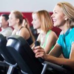 group of people cycling on exercise bikes at a gym