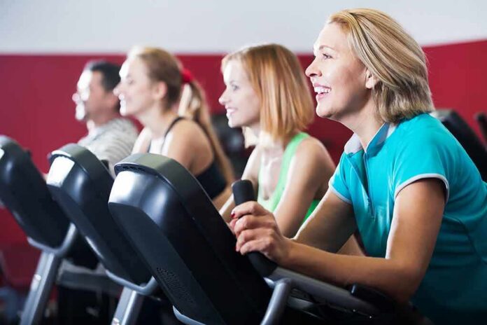 shutterstock_532327636 group of people cycling on exercise bikes at a gym