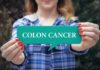 Colon Cancer Risk PLUMMETS With One Food Twist Person holding a teal speech bubble sign