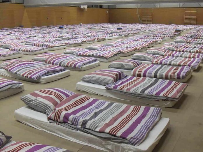 shutterstock_654873565 rows of mattresses with striped bedding in a large hall