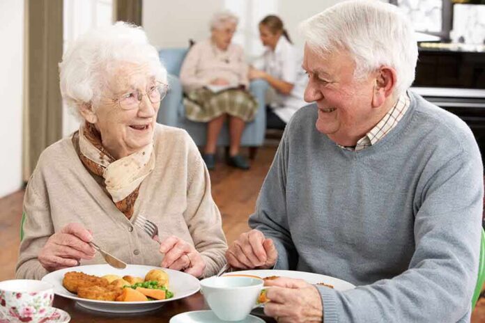shutterstock_73623583 Two seniors smiling while eating a meal together at a table