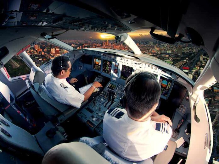 1783887752355-et8c06-shutterstock-512612131 Pilots in an airplane cockpit during city approach at sunset