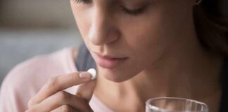Woman holding a white pill and a glass of water