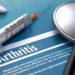 Syringe and stethoscope on arthritis document