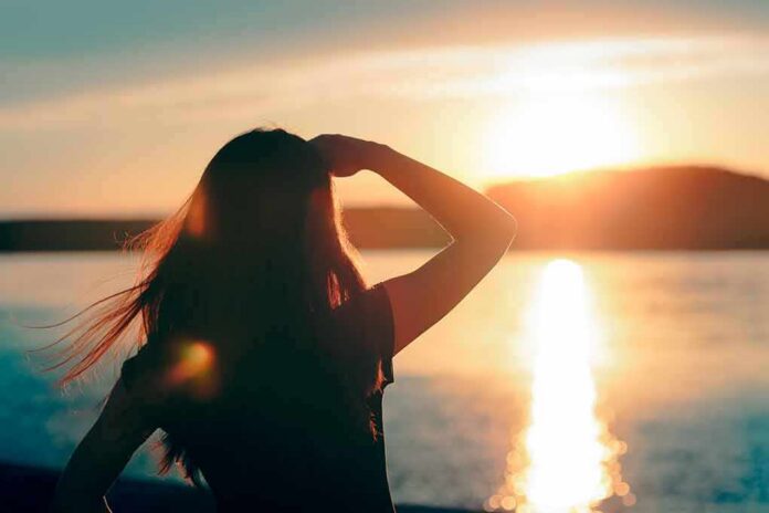 shutterstock_1011373993-1 Silhouette of a person looking at a sunset over water