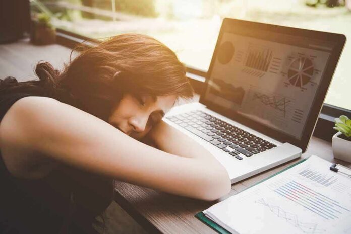 shutterstock_1023223072 Woman resting her head on desk beside an open laptop