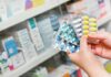Hands holding blister packs of assorted pills in a pharmacy
