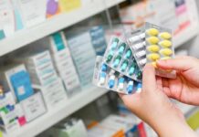 Antibiotics Linked To Lifelong Gut Chaos Hands holding blister packs of assorted pills in a pharmacy