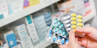 Hands holding blister packs of assorted pills in a pharmacy