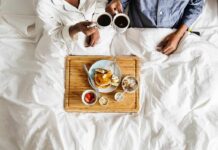 Breakfast in bed with two people holding coffee