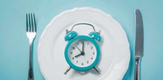 Alarm clock on a white plate with fork and knife