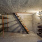 Concrete basement with shelves and a metal staircase