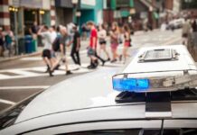 Federal Alert: Halloween’s Most Dangerous Time Window police car roof light bar with blue lights near a busy crosswalk