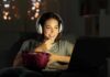 Daily Music, Stunning Brain Edge Woman wearing headphones watching a laptop with a bowl of popcorn