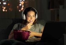 Daily Music, Stunning Brain Edge Woman wearing headphones watching a laptop with a bowl of popcorn