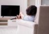 Hidden Muscle Damage From Sleep Apnea Person lying on a sofa holding a TV remote